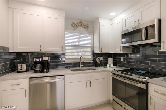 kitchen featuring white cabinetry, stainless steel appliances, a sink, and light countertops