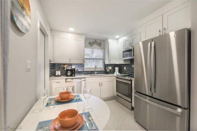 kitchen with stainless steel appliances, light countertops, a sink, and backsplash