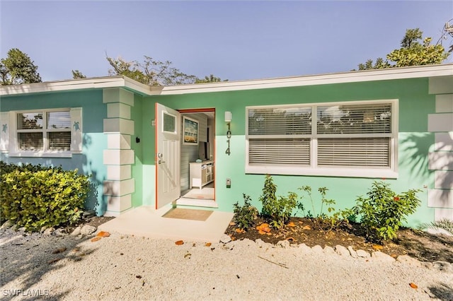 doorway to property featuring stucco siding