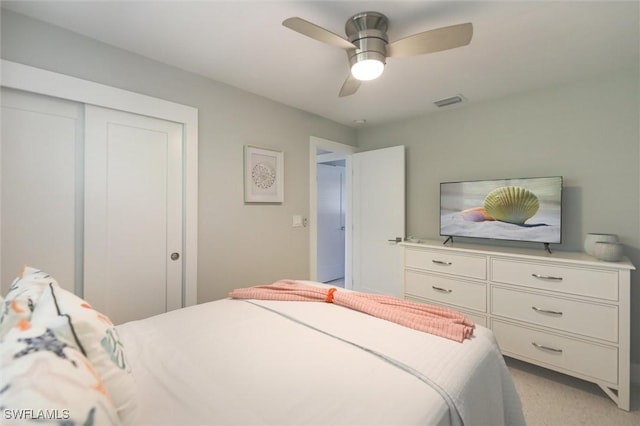 bedroom featuring ceiling fan, a closet, visible vents, and light colored carpet