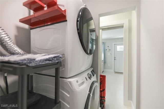 washroom featuring stacked washer / dryer, laundry area, and baseboards