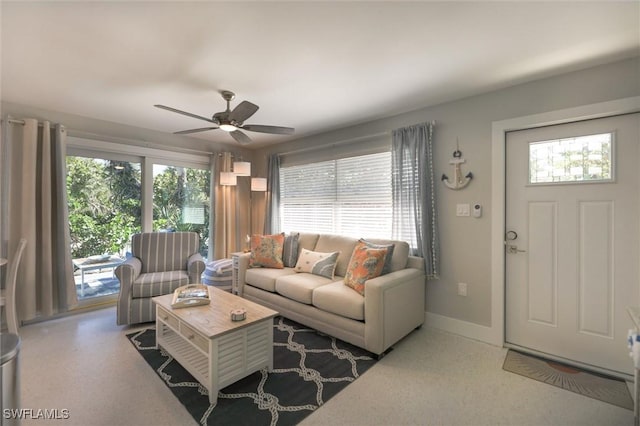 living room featuring baseboards, ceiling fan, and a healthy amount of sunlight