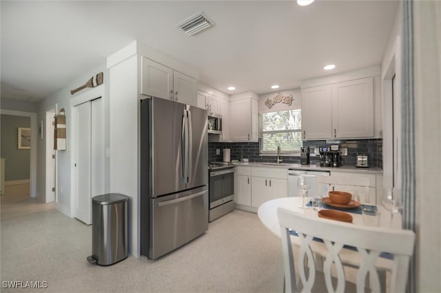 kitchen featuring a sink, visible vents, stainless steel appliances, and decorative backsplash