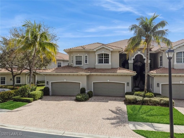 mediterranean / spanish-style house featuring decorative driveway, a tile roof, and stucco siding