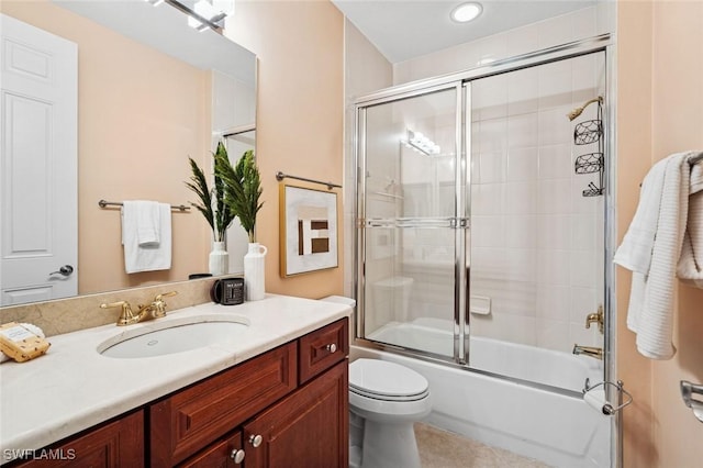 full bath with toilet, bath / shower combo with glass door, and vanity