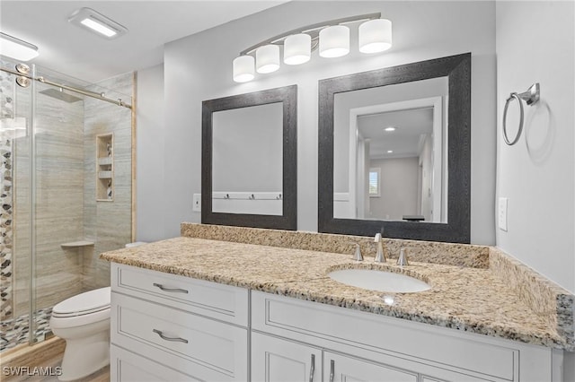 bathroom featuring a stall shower, vanity, toilet, and wood finished floors