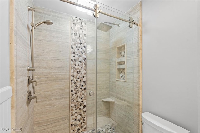 bathroom featuring toilet and a shower stall