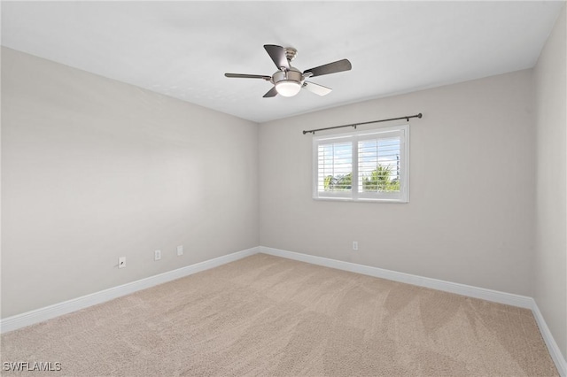 spare room with light carpet, a ceiling fan, and baseboards