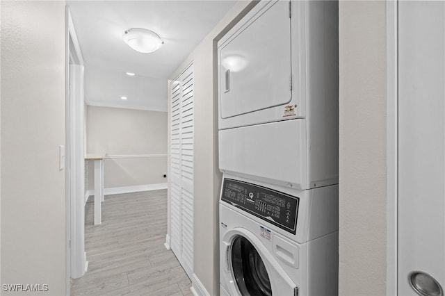 washroom featuring stacked washing maching and dryer, baseboards, laundry area, and light wood finished floors