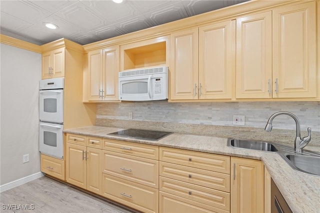 kitchen with white appliances, tasteful backsplash, baseboards, light wood-type flooring, and a sink