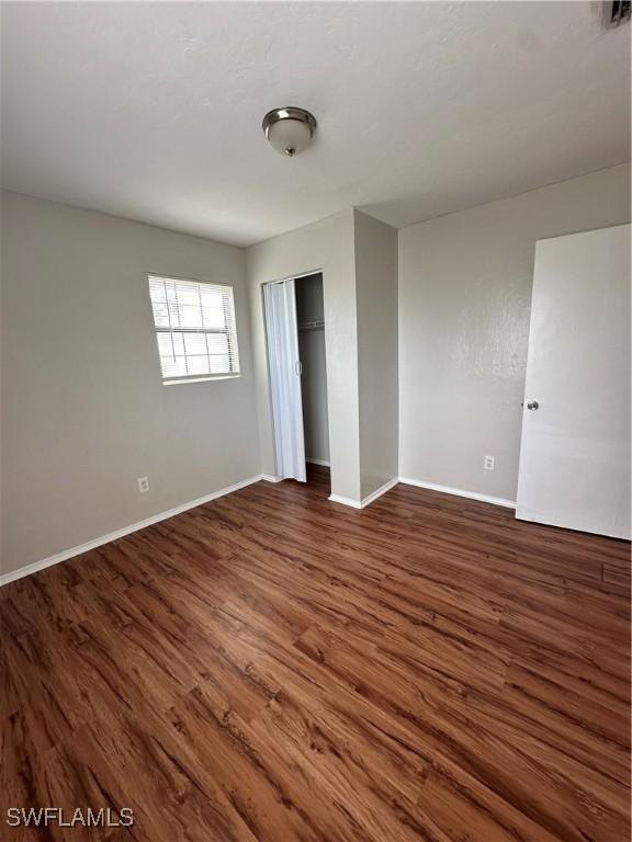 unfurnished bedroom with a closet, wood finished floors, and baseboards