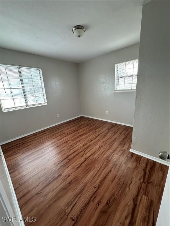 empty room with dark wood-style floors and baseboards