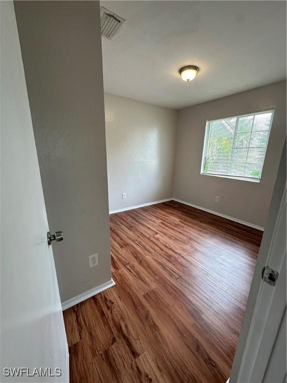 spare room featuring visible vents, baseboards, and wood finished floors