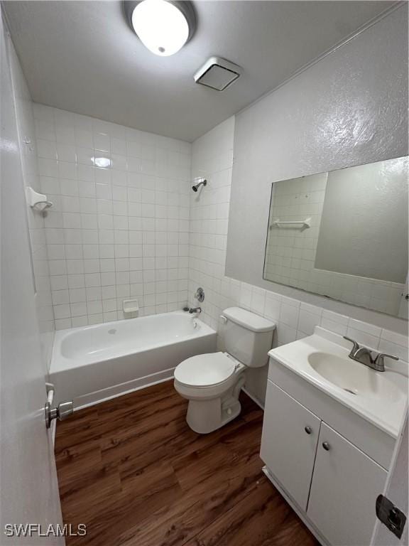 full bathroom featuring shower / tub combination, toilet, wood finished floors, vanity, and tile walls