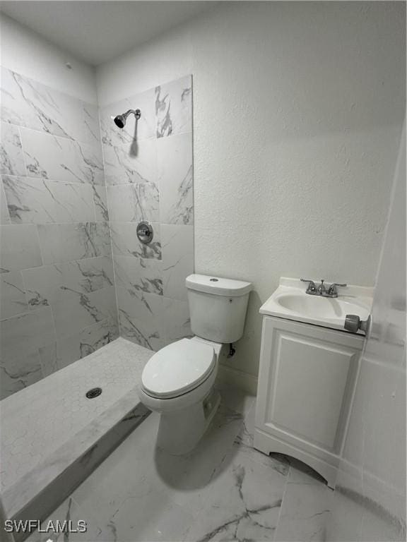 full bathroom with a textured wall, toilet, vanity, marble finish floor, and a shower stall