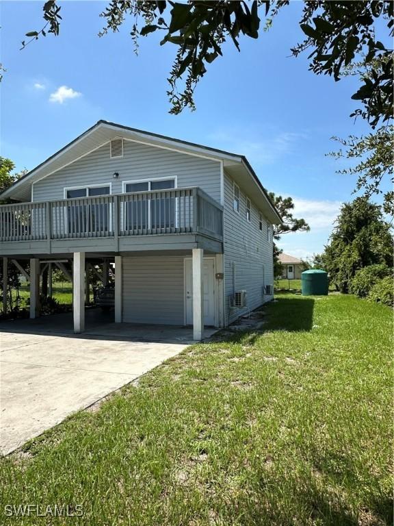 view of side of property with a lawn, a deck, a carport, and concrete driveway