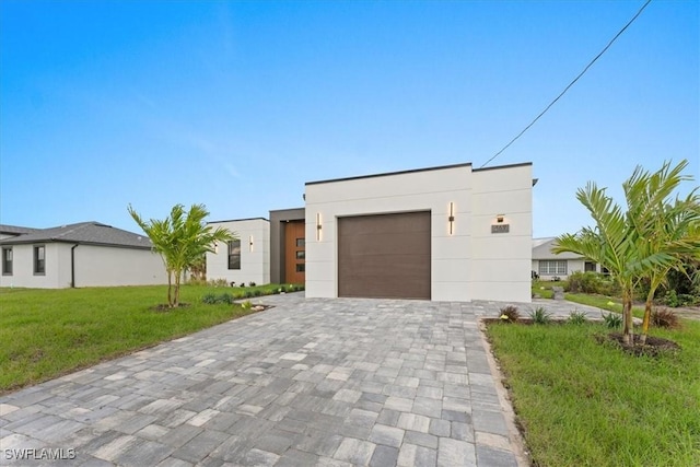 contemporary home with a garage, a front lawn, decorative driveway, and stucco siding