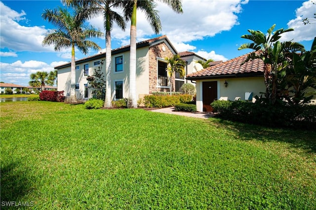 exterior space featuring a tiled roof, a front lawn, and stucco siding