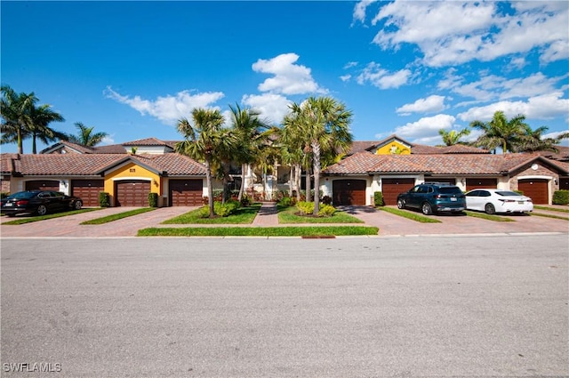 view of property featuring decorative driveway, an attached garage, and a tile roof