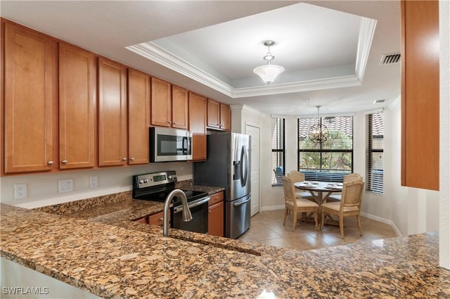 kitchen with stainless steel appliances, a raised ceiling, brown cabinets, and crown molding