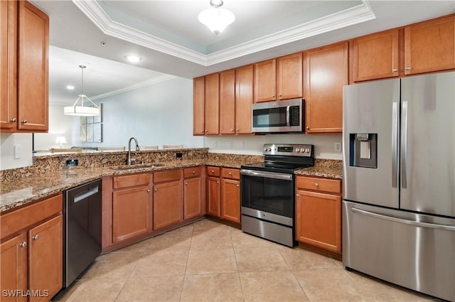 kitchen featuring appliances with stainless steel finishes, a tray ceiling, brown cabinetry, and a sink