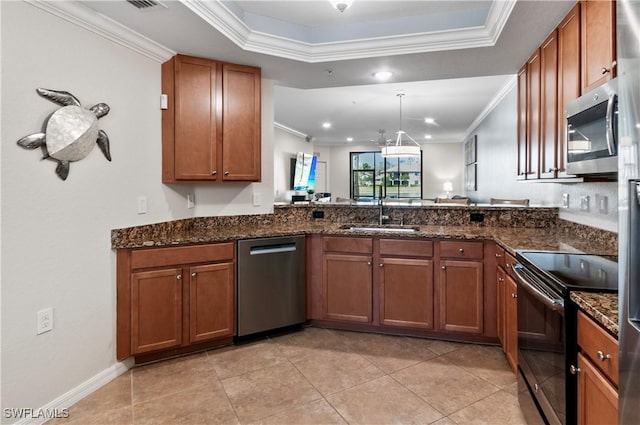 kitchen featuring a raised ceiling, stainless steel appliances, a sink, and brown cabinets