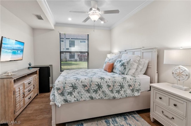 bedroom with ceiling fan, visible vents, crown molding, and wood finished floors