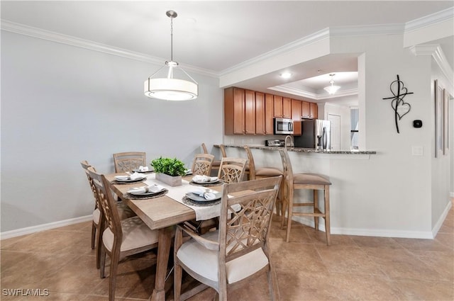 dining area with baseboards, ornamental molding, and a raised ceiling