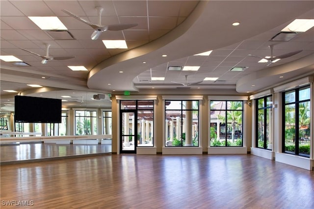 interior space with a ceiling fan, a paneled ceiling, visible vents, and wood finished floors