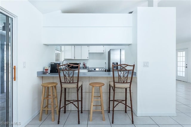 kitchen featuring a kitchen breakfast bar, stainless steel appliances, a peninsula, light countertops, and baseboards