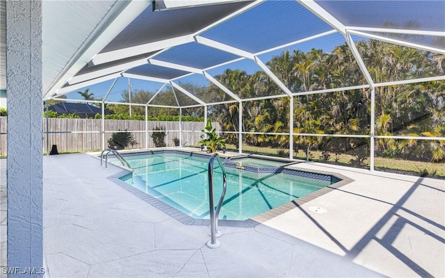 view of swimming pool featuring a patio area, glass enclosure, a pool with connected hot tub, and fence