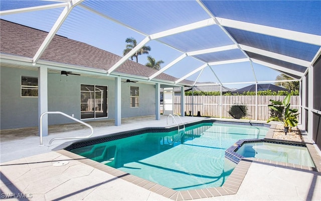 view of swimming pool featuring a pool with connected hot tub, ceiling fan, fence, a lanai, and a patio area