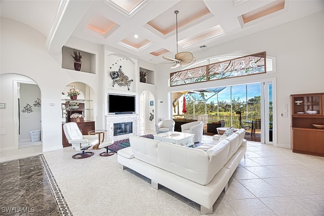 living area featuring baseboards, built in features, a ceiling fan, a sunroom, and a high ceiling