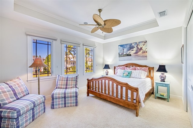 carpeted bedroom featuring a tray ceiling, visible vents, and baseboards