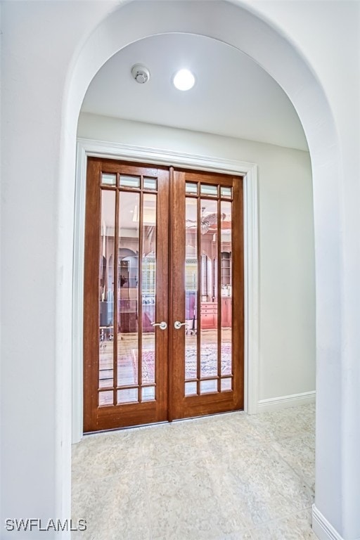 doorway to outside featuring arched walkways, french doors, and baseboards