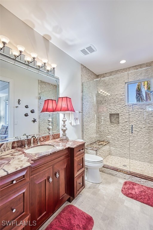 full bath with toilet, a stall shower, vanity, and visible vents