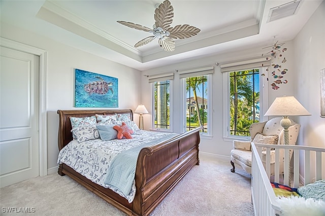 carpeted bedroom with ornamental molding, a tray ceiling, baseboards, and a ceiling fan