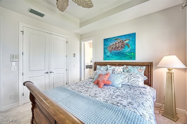 bedroom featuring a raised ceiling, light colored carpet, visible vents, a closet, and ornamental molding