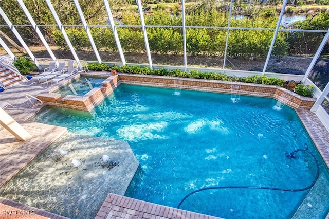 pool with glass enclosure, a patio area, and an in ground hot tub