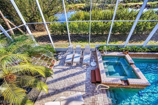 view of pool featuring a pool with connected hot tub, glass enclosure, and a patio