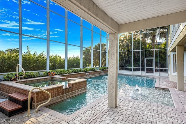 outdoor pool featuring glass enclosure, a patio, and an in ground hot tub