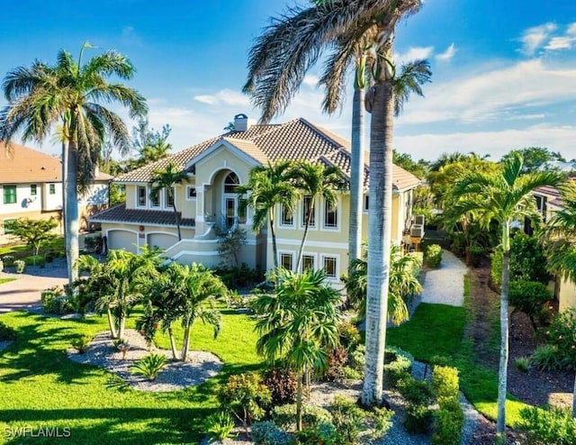 view of front of house with a garage, a tile roof, a front lawn, and stucco siding