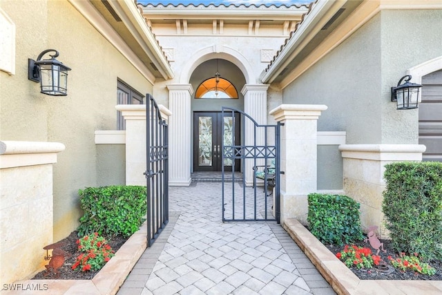 doorway to property featuring a gate, a tiled roof, and stucco siding