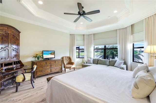 bedroom with ornamental molding, light wood-type flooring, a raised ceiling, and ceiling fan