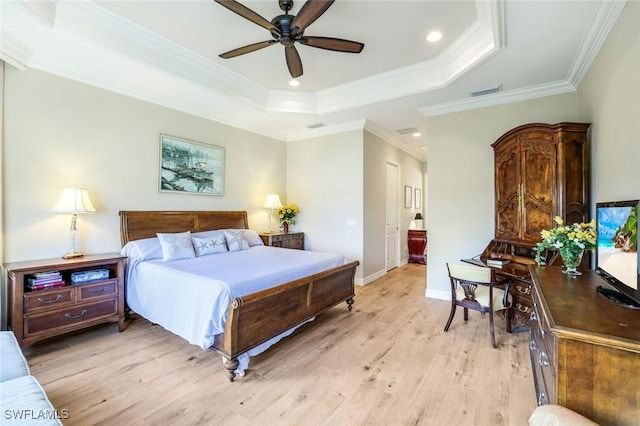 bedroom featuring visible vents, baseboards, ornamental molding, a tray ceiling, and light wood finished floors