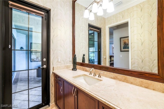 bathroom featuring ornamental molding, vanity, and wallpapered walls