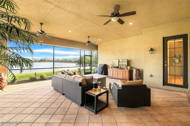 view of patio featuring a lanai, a water view, an outdoor hangout area, and a ceiling fan