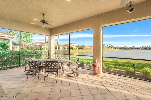 sunroom / solarium with a water view and a ceiling fan