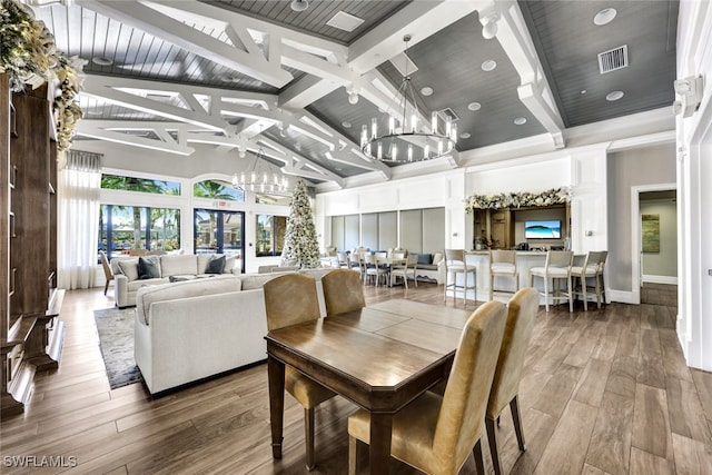 dining space featuring an inviting chandelier, visible vents, high vaulted ceiling, and wood finished floors