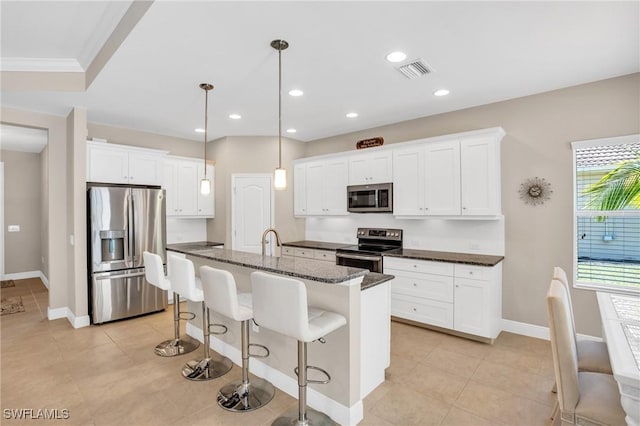 kitchen with visible vents, a kitchen bar, a center island with sink, white cabinetry, and appliances with stainless steel finishes